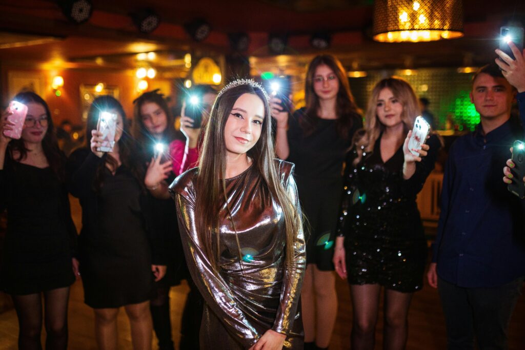 A glamorous party scene with elegantly dressed guests capturing moments with smartphones.