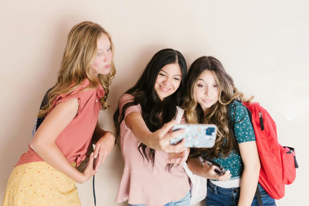 Three teenage girls smiling while taking a selfie, capturing a fun moment of friendship.